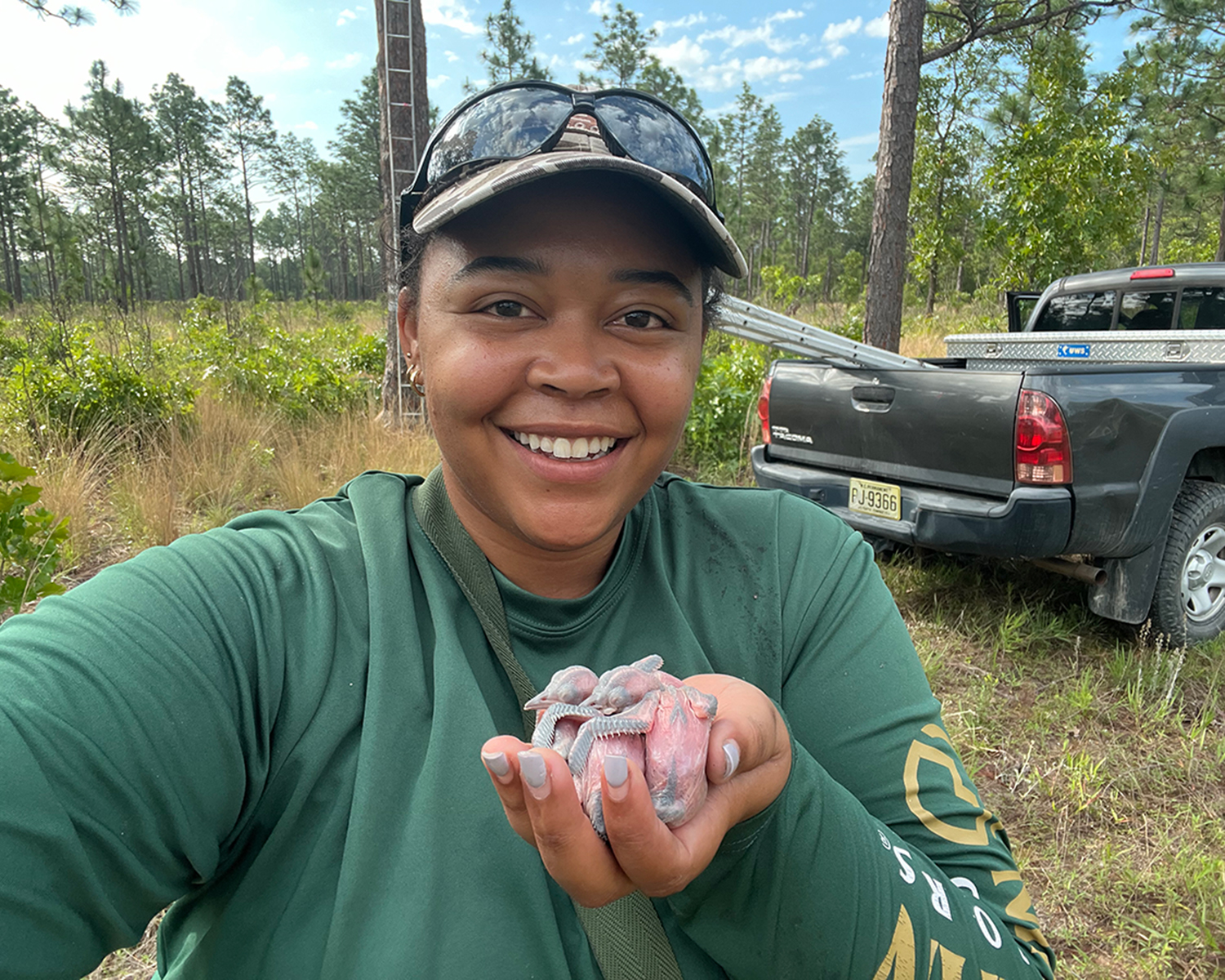 Smiling woman holding two featherless bird hatchlings