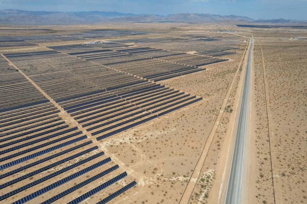 Aerial image showing solar arrays, fence line and roads through a Nevada desert.