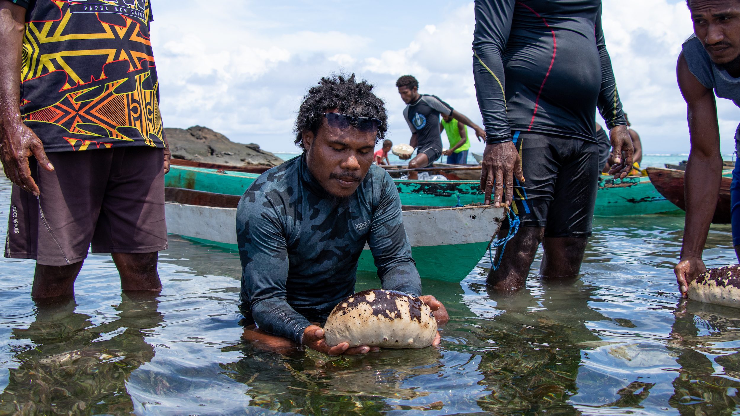 A man in the water holding a large sea cucumber.