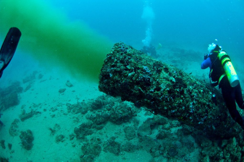 underwater photograph showing a diver near an offshore outfall sewer pipe spewing material into the ocean