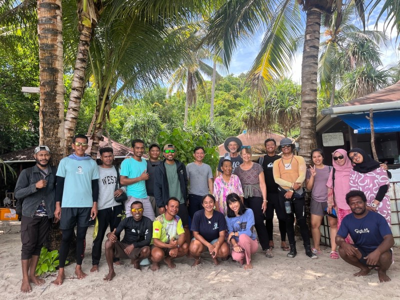 A group of men and women standing under palm trees on a tropical island.