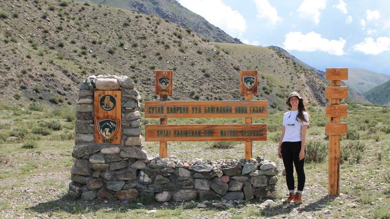 A women standing by an outdoor sign in Mongolia