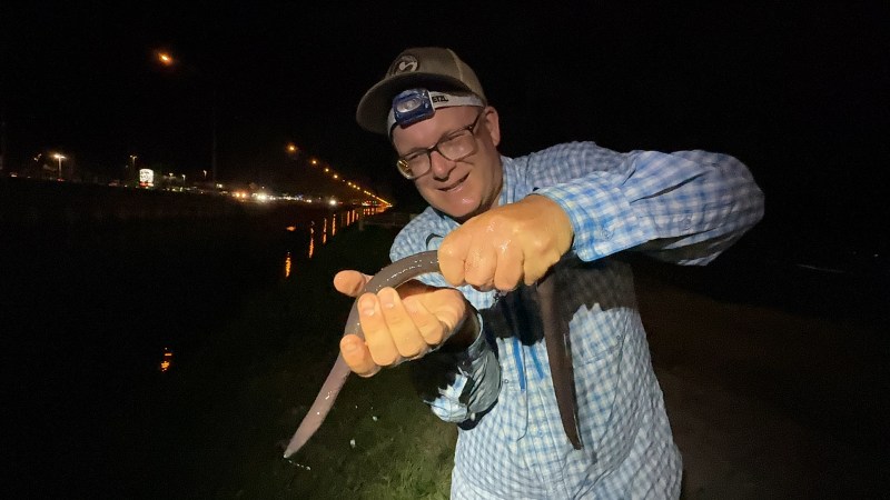 A man holding a long eel-like creature